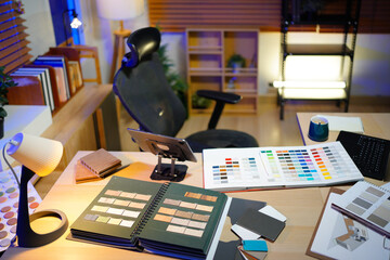 Interior designer workspace table and architecture laptop with mood board materials and colorful swatch color for color selection. Modern interior design office. In night