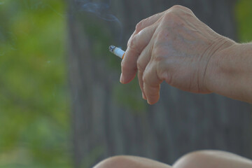 A smoldering cigarette in a woman's hand