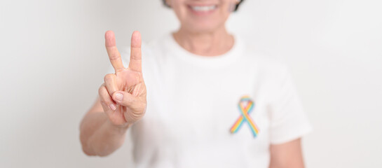 Elderly with LGBTQ Rainbow ribbon for concept of June Pride month, April Autism Awareness, All cancer Awareness, February World Cancer day, October World Hospice and Palliative care day and Survivor