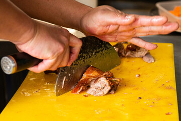 Professional chef slicing traditional Peking duck with a cleaver, showcasing crispy skin, tender meat, and authentic Chinese culinary craftsmanship.