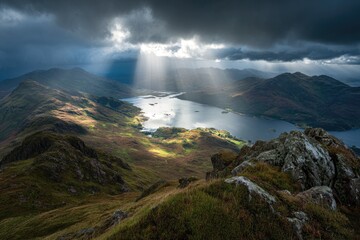 Mountain vista with dramatic sky, sun rays, lake below, rugged, scenic landscape