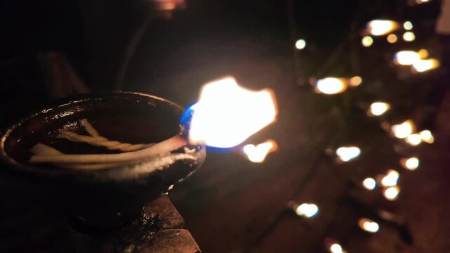 Cinematic wide shot of a row of traditional coconut oil lamps burning at a Buddhist temple in Sri Lanka, creating a serene atmosphere for a religious festival.
