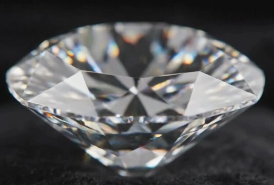 Luxurious close up macro shot of beautiful perfectly cut clear round brilliant diamond sparkling slowly on black background showing spectacular clarity dispersion and fire light reflection