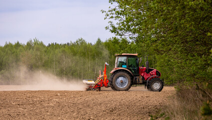 Obraz premium Tractor drilling seeding crops at farm field. Agricultural activity. Tractor spraying pesticides at soy bean fields.