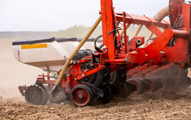 Precision inline seeder. A row seeder. Seed drill. Tractor with mounted seeder performing direct seeding of crops on plowed agricultural field. Farmer is using farming machinery for planting process. © NastyaPhoto