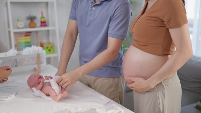 Pregnant woman and husband learn how to wrap a baby at maternal center. 