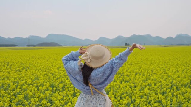 Young happy woman tourist enjoying the canola fields while traveling in Luoping, China