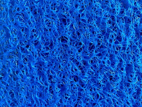 Blue plastic mesh texture background with tangled synthetic fiber pattern.