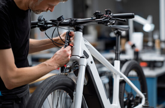 A mechanic repairing an electric bicycle with focus on frame and components in workshop setting
