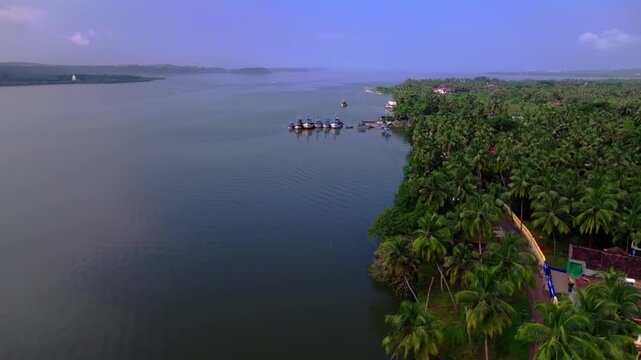 Zuari river with coconut trees and fishing boats at agacaim, goa, india. day time, zib shot, drone shot, 4k.