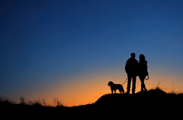 Silhouette of a couple and their dog atop a hill at dusk against a gradient sky