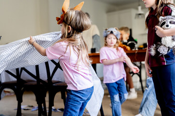 Young girl covering chairs with fabric for makeshift tent inside home