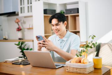 Asian man managing personal finance and household budget at home office. Smart money management, online banking, savings and modern work from home