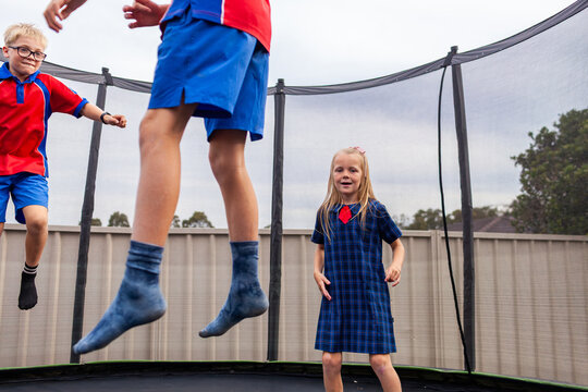 Aussie kids playing together after school bouncing on backyard trampoline at home