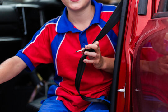 school child holding buckle of lap and sash belt ready to get buckled into car