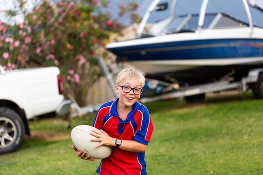 Australian schoolboy playing with ball in suburban front yard on overcast day after school