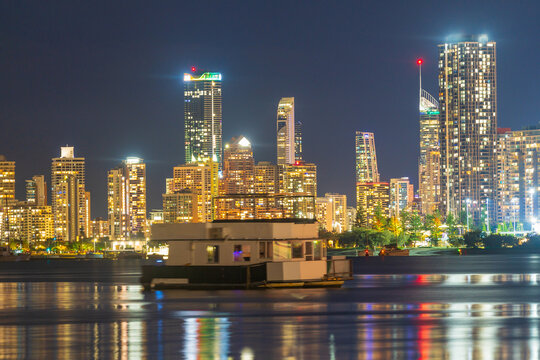 Highrise buildings lit up after dark reflecting in a calm river