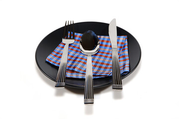 Elegant table setting with silverware arranged on a colorful checkered napkin on a black plate,...