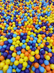 Vibrant balls fill a ball pit with colorful plastic orbs in shades of blue, yellow, orange, and purple from a top-down viewpoint