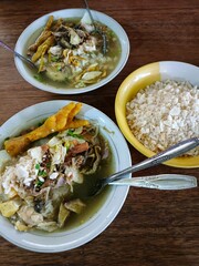 A bowl of soup with rice and another bowl on a wooden table