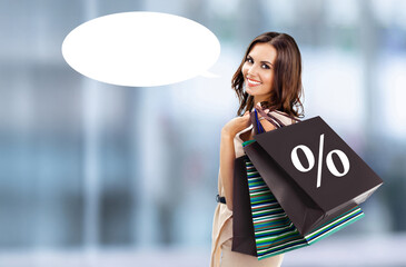Ad concept image - shopping cute brunette woman. Smile girl carry bags with % percentage sign, blurred mall background with free space white empty mockup speech bubble. Black Friday sale
