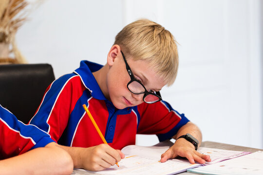 Primary aged boy working on homework workbook after school