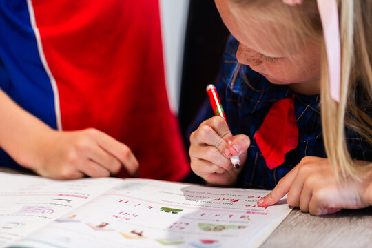 Older brother schoolboy helping tutor younger sister with homework