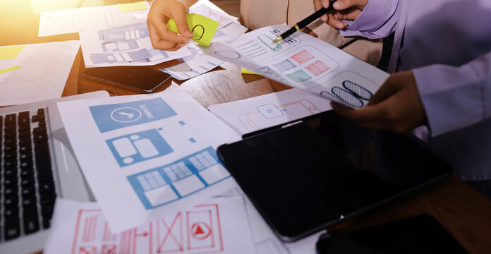 Close up ux developer and ui designer brainstorming about mobile app interface wireframe design on table with customer breif and color code at modern office.Creative digital development agency. - Powered by Adobe