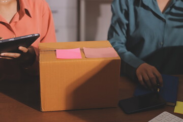 Startup SME small business entrepreneur of freelance Asian woman wearing apron using laptop and box to receive and review orders online to prepare to pack sell to customers, online sme business ideas.