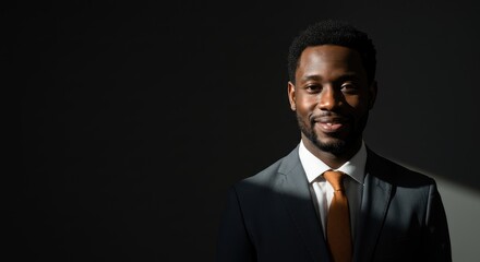 A dark-suited man smiles warmly at the camera