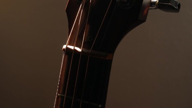 Guitar Headstock Side View: Wooden Neck with Tuning Pegs and Strings Close-up on Classic Acoustic Musical Instrument
