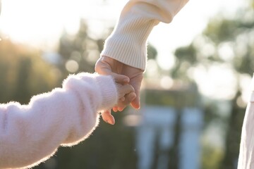 Mother and daughter holding hands outdoors, Mom hand lead his kid walking together. Family. Childhood development and growth with love for child, caring mom, happy family kid dream, support