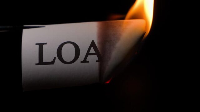 Repayment of a loan or debt. Burning paper with the word LOAN, close-up on a black background