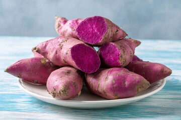 A vibrant display of fresh purple sweet potatoes, some whole and others artfully cut to reveal their striking, deep magenta flesh, are neatly arranged on a pristine white plate. This visually appealin