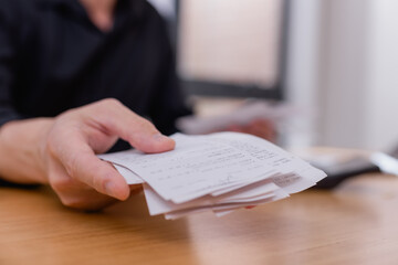 businessman holding and organizing receipts and invoices at desk, managing financial records tracking business expenses in office setting. Budget and accounting concept.