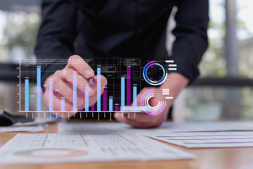 Businessman analyzing digital bar and pie charts using futuristic virtual interface, reviewing big data financial analytics for business strategy in modern office setting.