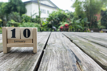wooden cube calendar for January 10th place on old table in sunny garden background