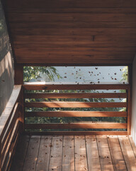 Wooden balcony with a view of butterflies fluttering near greenery in a sunny setting