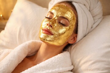 Golden Serenity: A woman reclines in peaceful bliss, enveloped in the luxurious tranquility of a golden face mask, wrapped in a plush towel, showcasing self-care and relaxation.