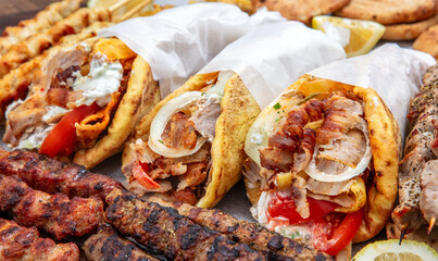 Gyro sliced meat pita bread wraps, pork skewers, and kebab, traditional greek food platter, closeup