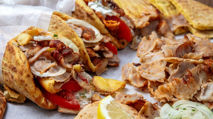 Gyros doner shawarma wraps stuffed with roasted meat, onions, tomato and tzatziki, closeup
