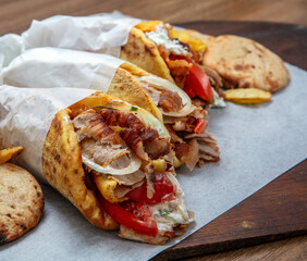 Doner gyro or shawarma wraps stuffed with roasted meat, onions, tomato and tzatziki, closeup