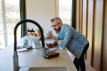 Man working from home office, drinking coffe and working on laptop.