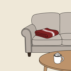 Cozy living room scene with a sofa, blanket, and hot drink on the table