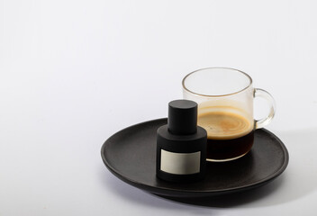 A sleek black men's cologne bottle elegantly paired with a fresh cup of espresso on a dark ceramic try. Ideal for urban lifestyle and morning grooming routine content.