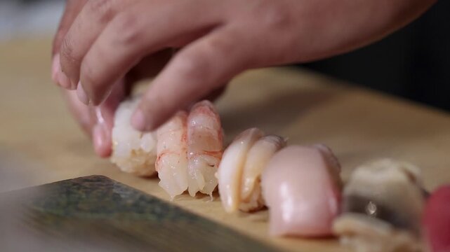 Chef Carefully Arranging Fresh Nigiri Sushi on a Wooden Board