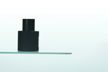 Unbranded black packaging perfume bottle on a white background with a clean surface reflection. Represents sophistication and simplicity in the beauty and personal care industry.