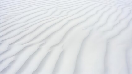 Obraz premium Aerial view of undulating white sand dunes with soft shadows and a minimalist aesthetic