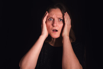 Woman with surprised and scared face holding head with hands. Concept of fear, shock, anxiety, and stress for mental health content.
