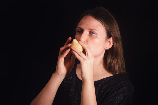 Woman playing ocarina on black background. Musical instrument for music education and creative pastime.